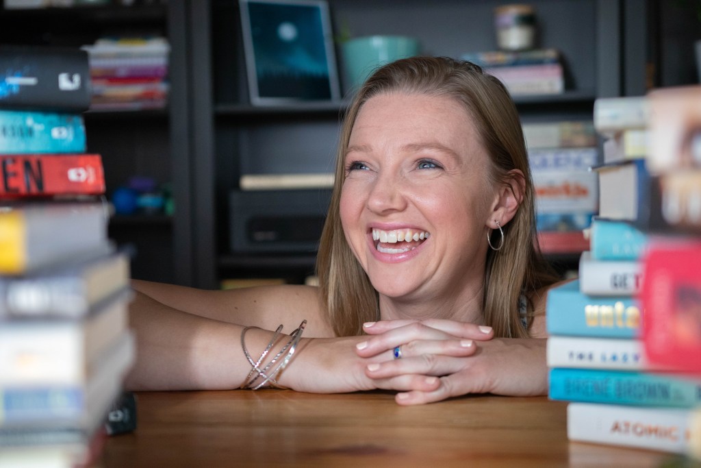 Photo of Ashleyne Seitz with piles of books